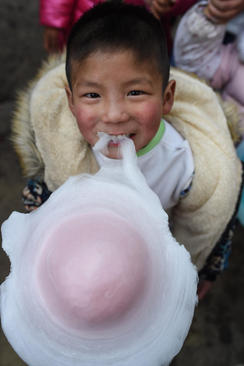 کودک روستایی چینی در حال خوردن آب نبات پنبه ای (پشمکی) در جشن سال نو چینی